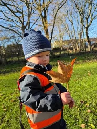bloom childcare child holding autumn leaf outdoors
