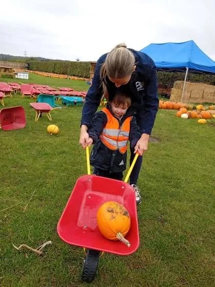 bloom childcare practitioner and child picking pumpkins