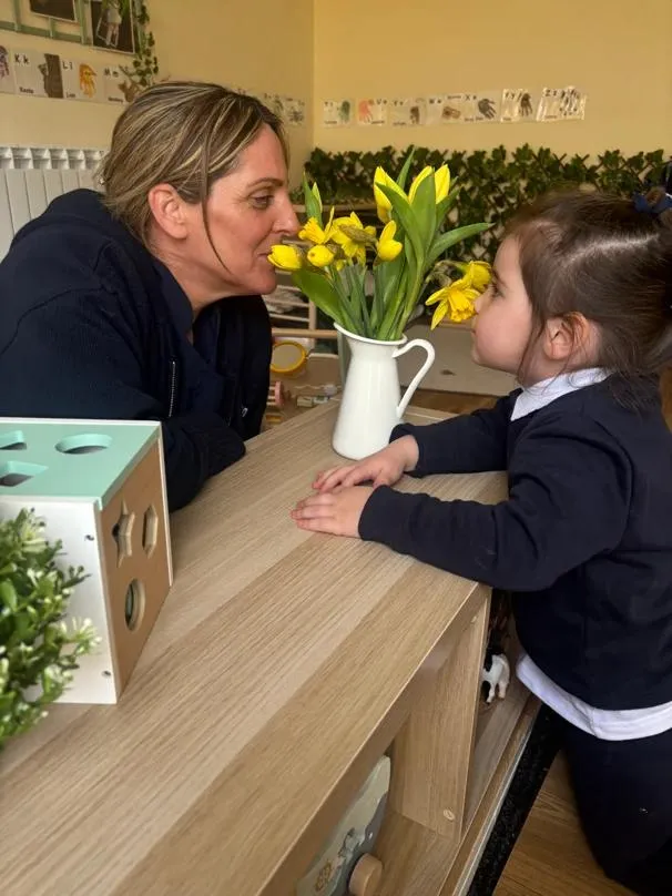 bloom childcare practitioner and child with yellow flowers